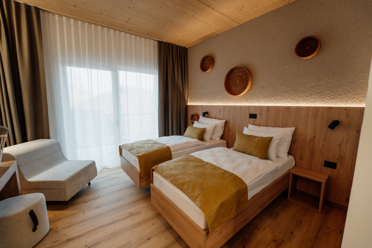 Soba z ločenima posteljama in naslanjačem v Hotelu Narcisa