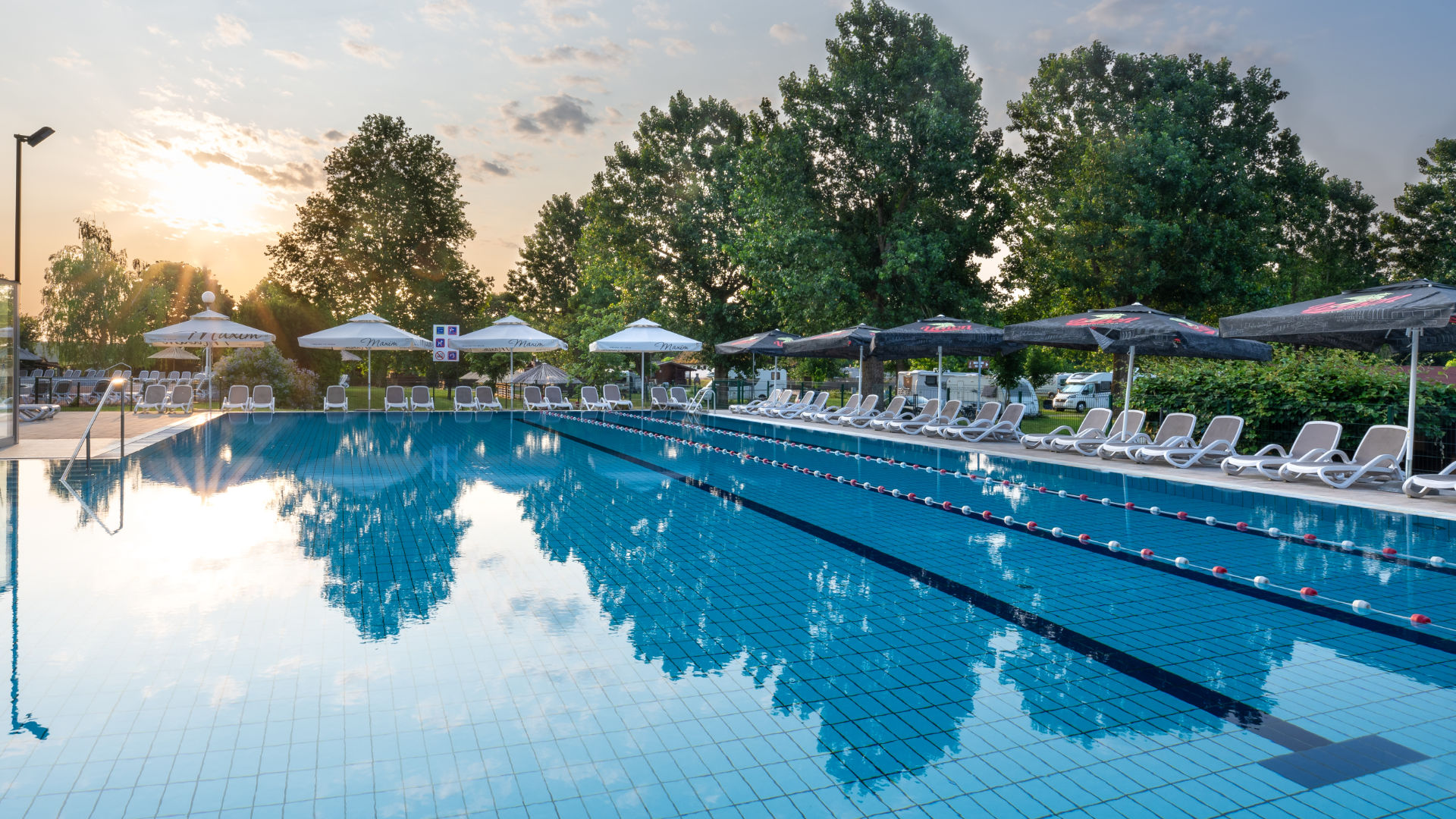 Bazeni Terme Banovci 3 Vanjski termalni bazen s ležaljkama i suncobranima u zalazak sunca